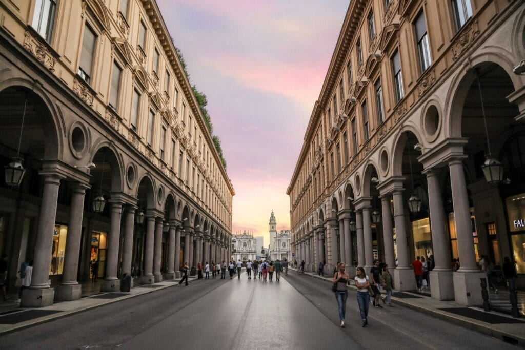 Arkady Via Roma w Turynie o zachodzie słońca, w głębi kościoły na Piazza San Carlo