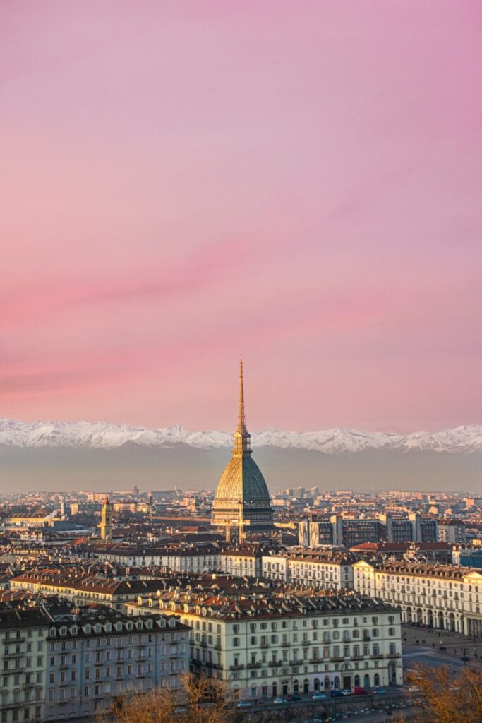 Mole Antonelliana o różowym zachodzie słońca, za miastem ściana Alp