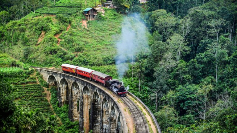 Ella - Sri Lanka. Pociąg wędruje malowniczymi, zielonymi górami przez las tropikalny z klasycznymi, czerwonymi wagonami i historycznym tunelem.