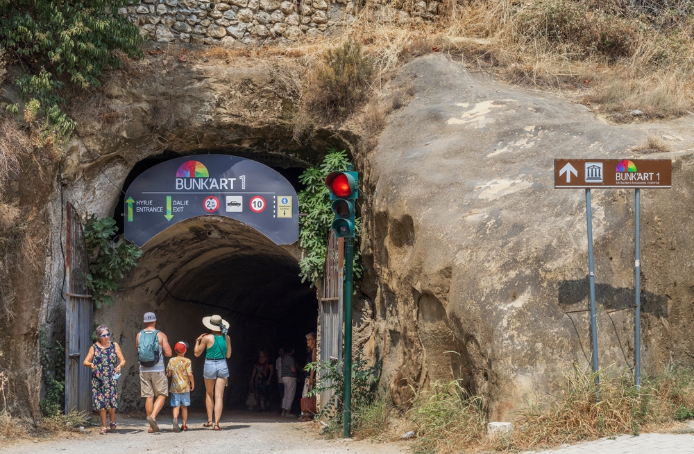 Wejście do muzeum Bunk Art 1 w Tiranie, tunel w zboczu i turyści przed bramą
