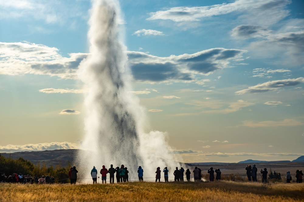 Gejzer Strokkur w Islandii, erupcja wody na tle zielonych wzgórz