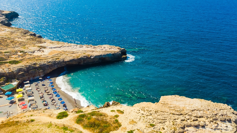 Skalna zatoka w Rethymno z żwirową plażą i turkusową wodą pod klifem