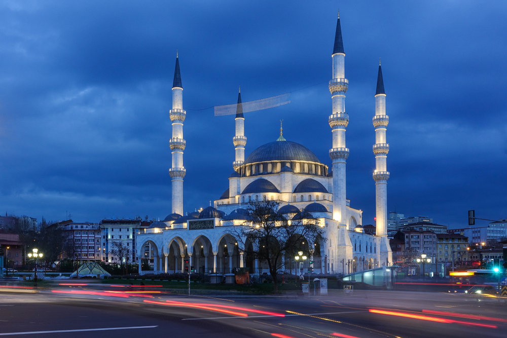 Oświetlony meczet z czterema minaretami nocą, otoczony miejską zabudową i śladami świateł samochodów, Ankara Turcja Melike Hatun