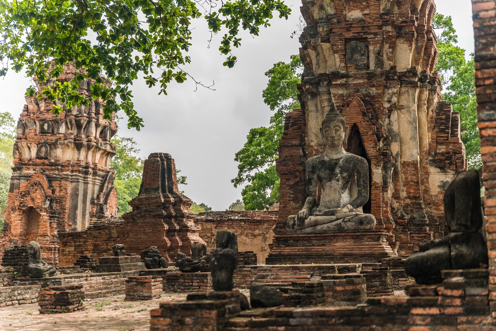 Główny prang i posąg Buddy wśród ruin Wat Mahathat w Ayutthai