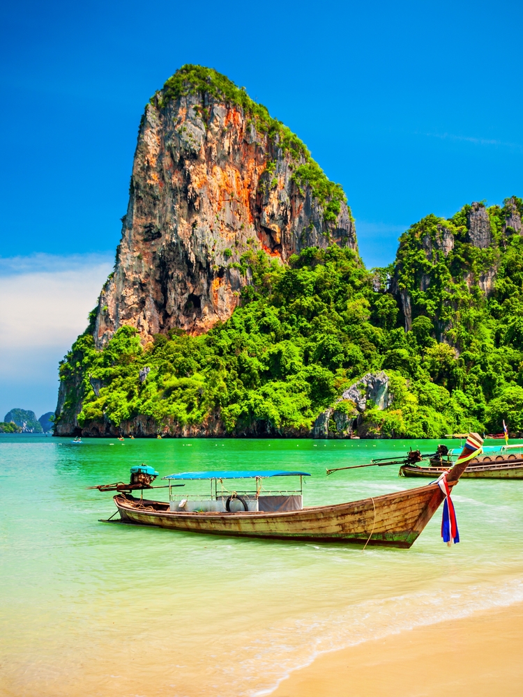 Łodzie przy plaży z wapiennymi skałami w rejonie Koh Lanta
