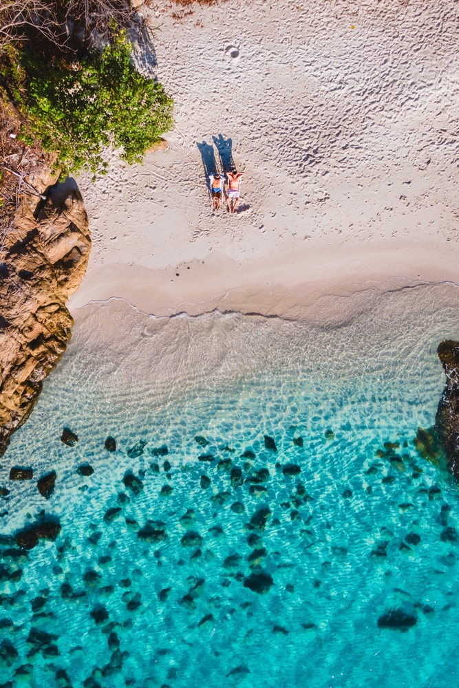 Para na leżakach na białej plaży Koh Samet, przejrzysta turkusowa woda z lotu ptaka