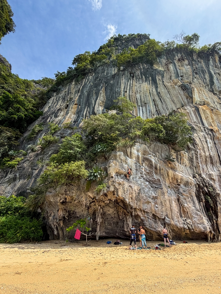 Wspinacze przygotowujący się do wejścia na wapienną ścianę nad plażą na Railay