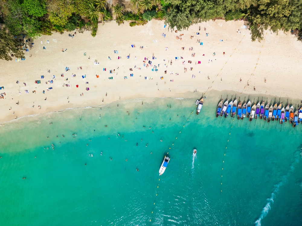 Plaża Railay West z lotu ptaka z rzędem łodzi longtail i kąpiącymi się
