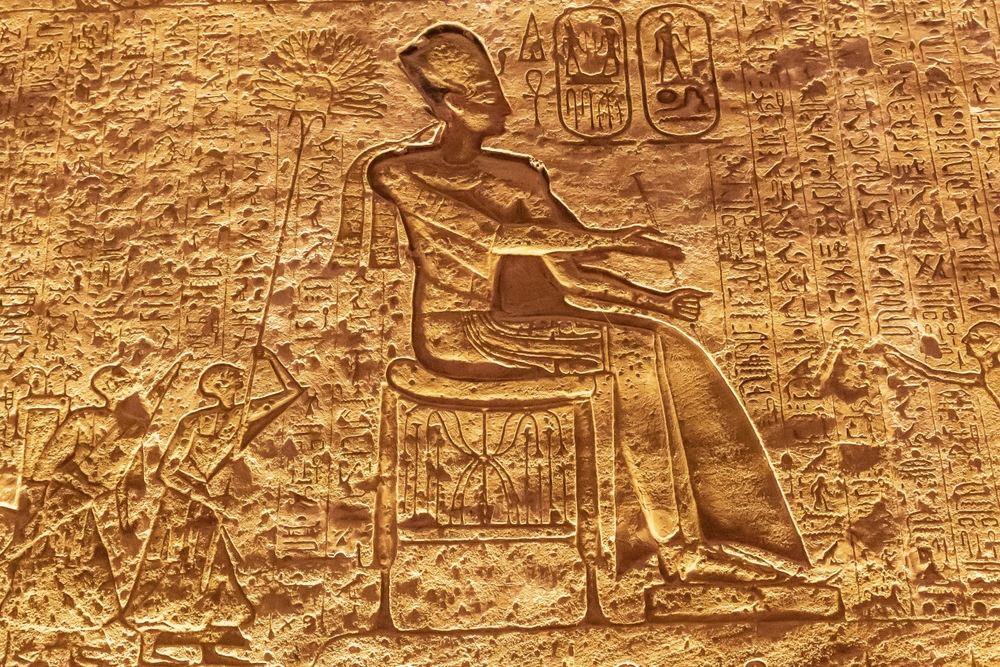 Płaskorzeźba na ścianie świątyni w Abu Simbel: postać na tronie wśród hieroglifów i kartuszy
