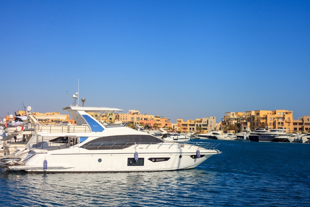 Biały jacht motorowy przy nabrzeżu Abu Tig Marina w El Gounie, w tle piaskowa zabudowa