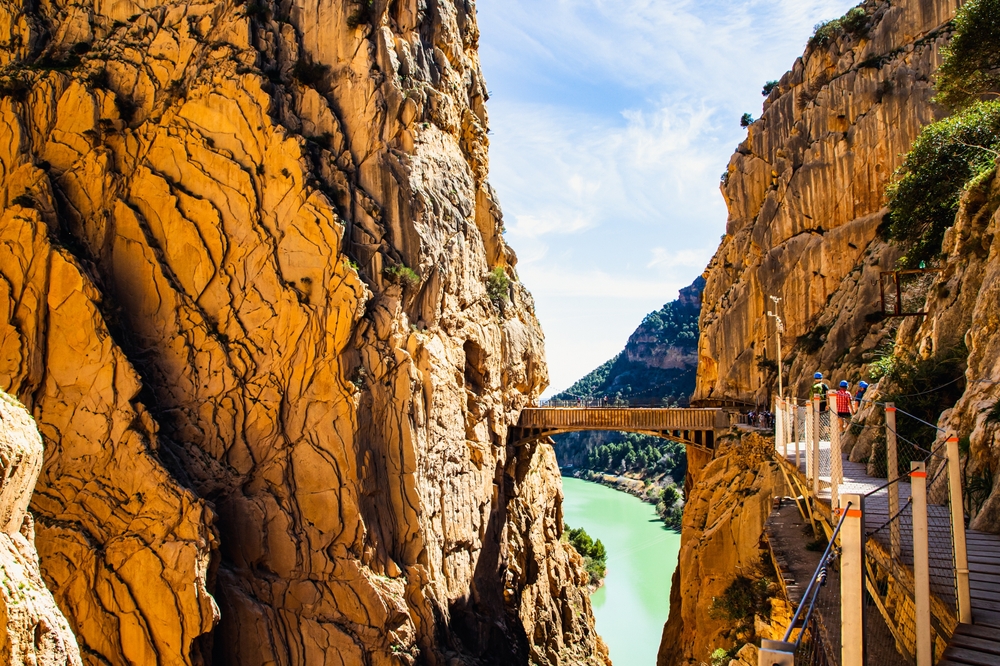 Most wiszący Caminito del Rey nad wąwozem, w dole zielona rzeka między pionowymi ścianami
