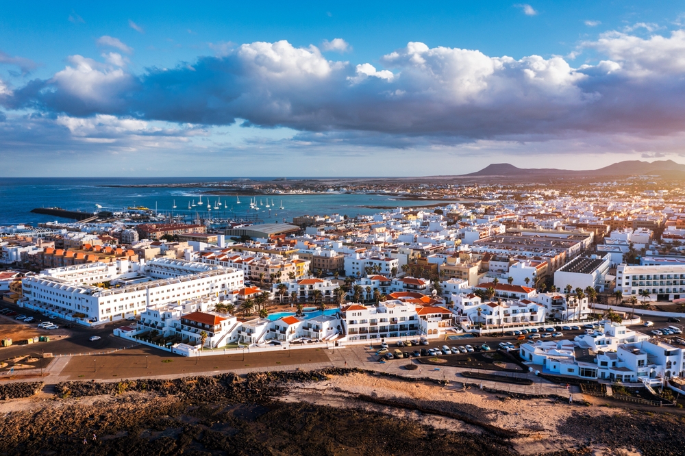Panorama Corralejo z lotu ptaka z portem, białą zabudową i wyspami na horyzoncie