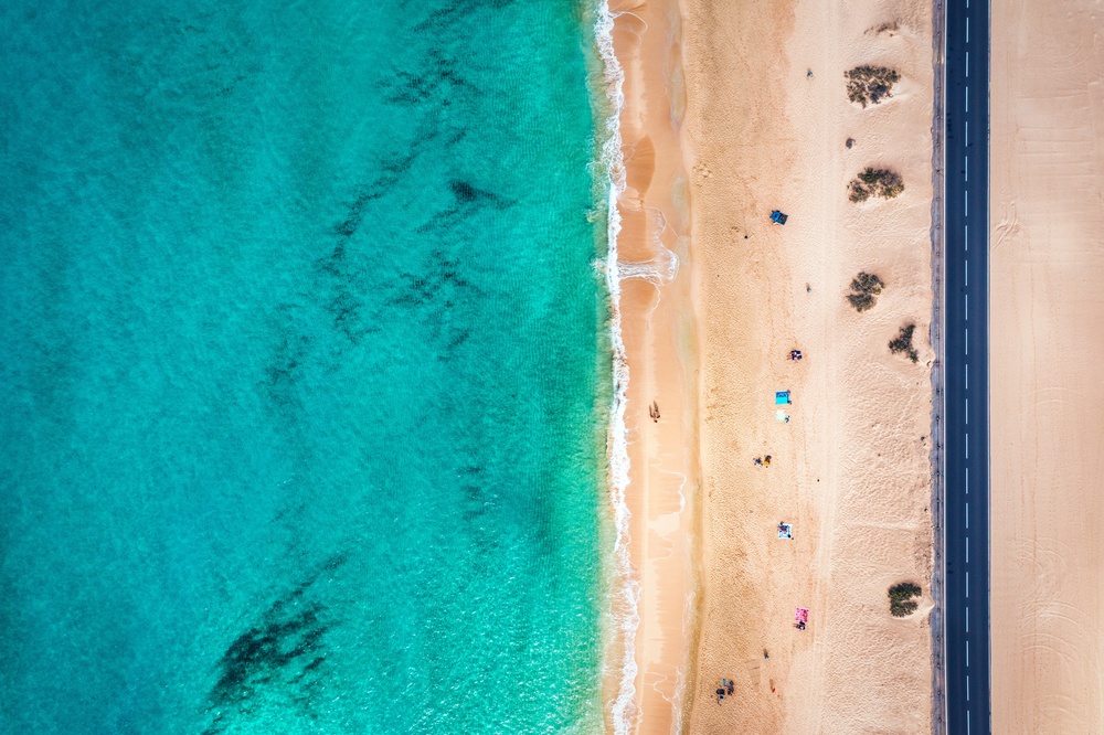 Plaża przy parku wydmowym Corralejo z lotu ptaka, turkusowa woda i droga FV-1