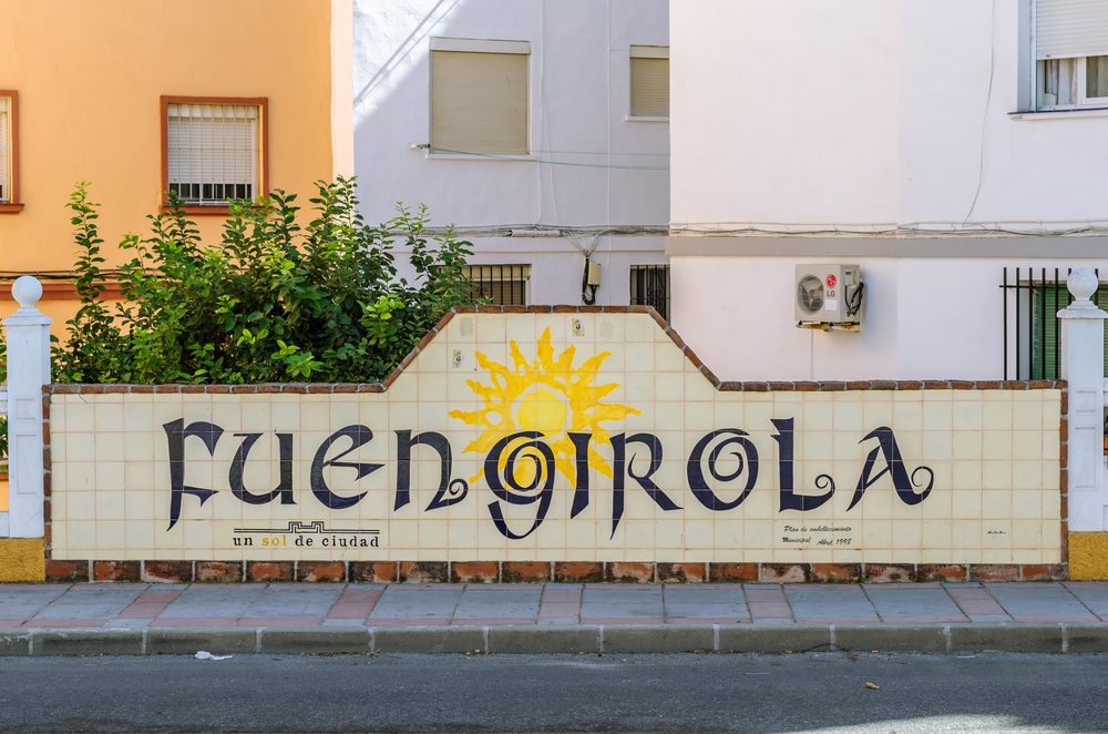 Ceramiczna tablica z napisem Fuengirola i słońcem na murku przy ulicy