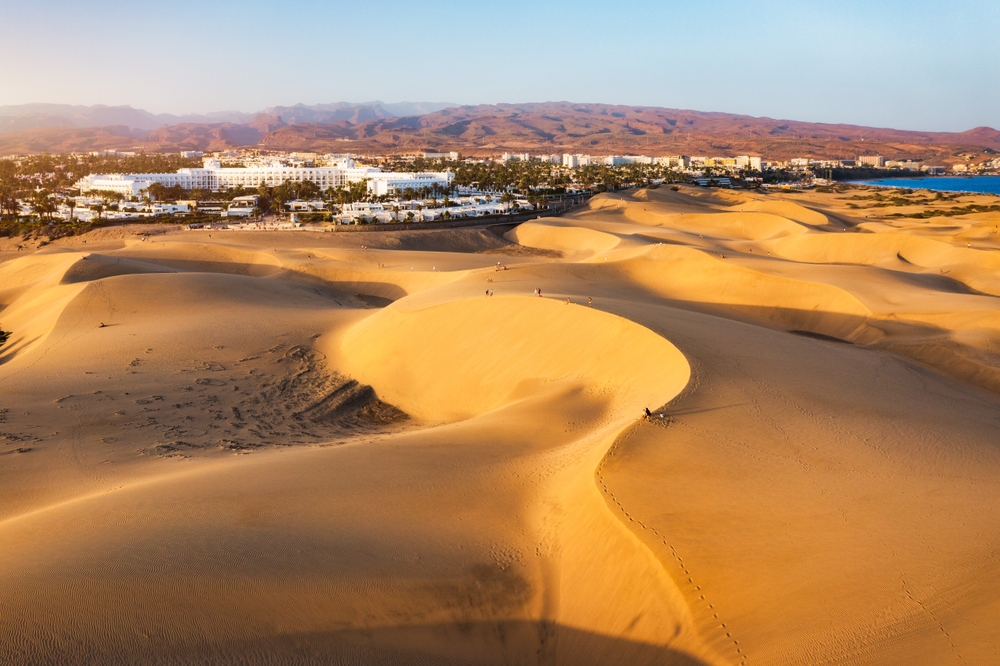 Wydmy Maspalomas o wschodzie słońca, w tle hotele Playa del Inglés i góry Gran Canarii
