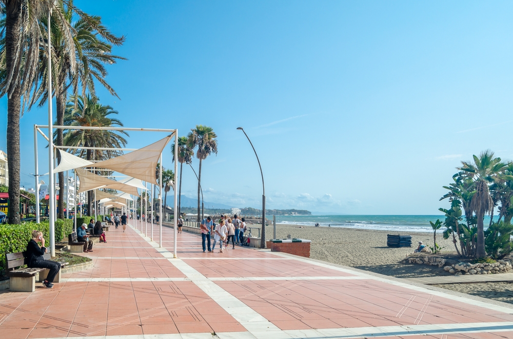 Nadmorska promenada w Esteponie z żaglami przeciwsłonecznymi, obok szeroka piaszczysta plaża