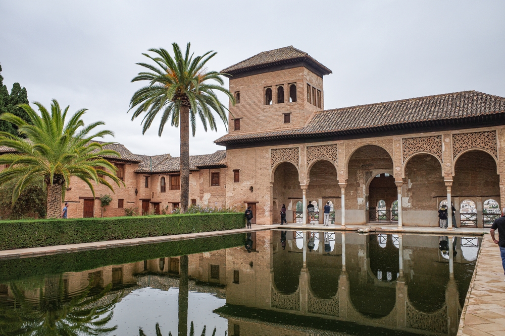 Palacio del Partal w Alhambrze, portyk odbity w sadzawce i palma obok