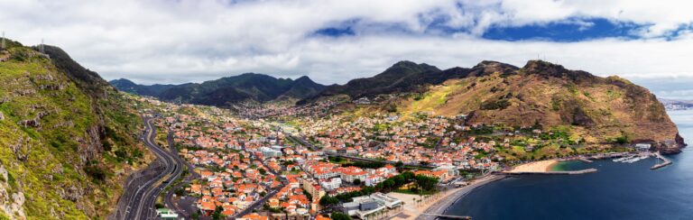 Panorama doliny Machico, zabudowa miasteczka i piaszczysta plaża nad zatoką