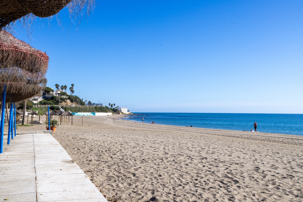 Plaża w La Cala de Mijas poza sezonem, parasole z trzciny i pusty piasek nad spokojnym morzem