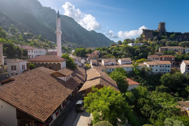 Dachy starego bazaru w Krui z minaretem meczetu, w tle zamek na skale i góry