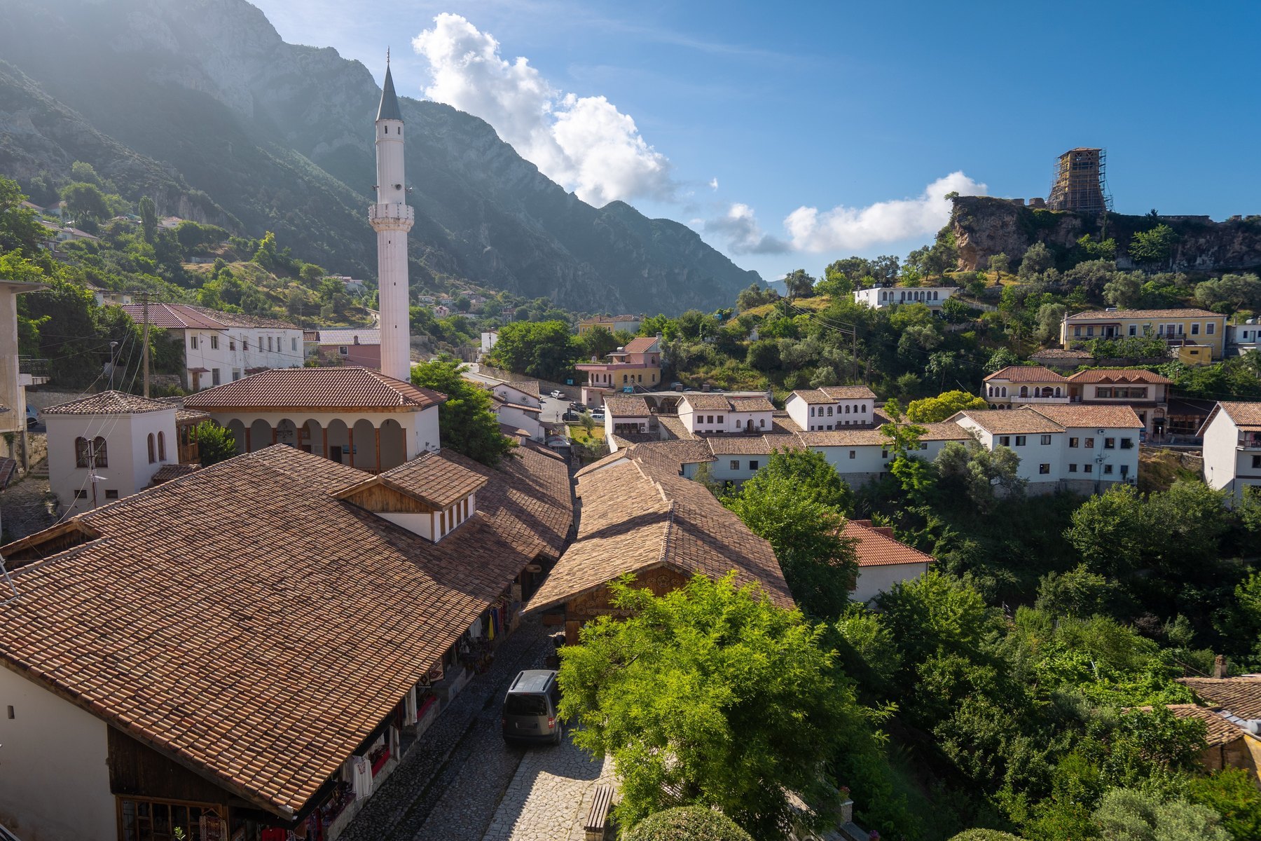 Dachy starego bazaru w Krui z minaretem meczetu, w tle zamek na skale i góry