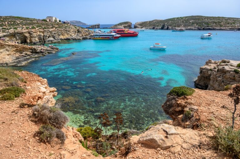 Turkusowa woda Blue Lagoon na Comino, łodzie wycieczkowe i skaliste brzegi zatoki
