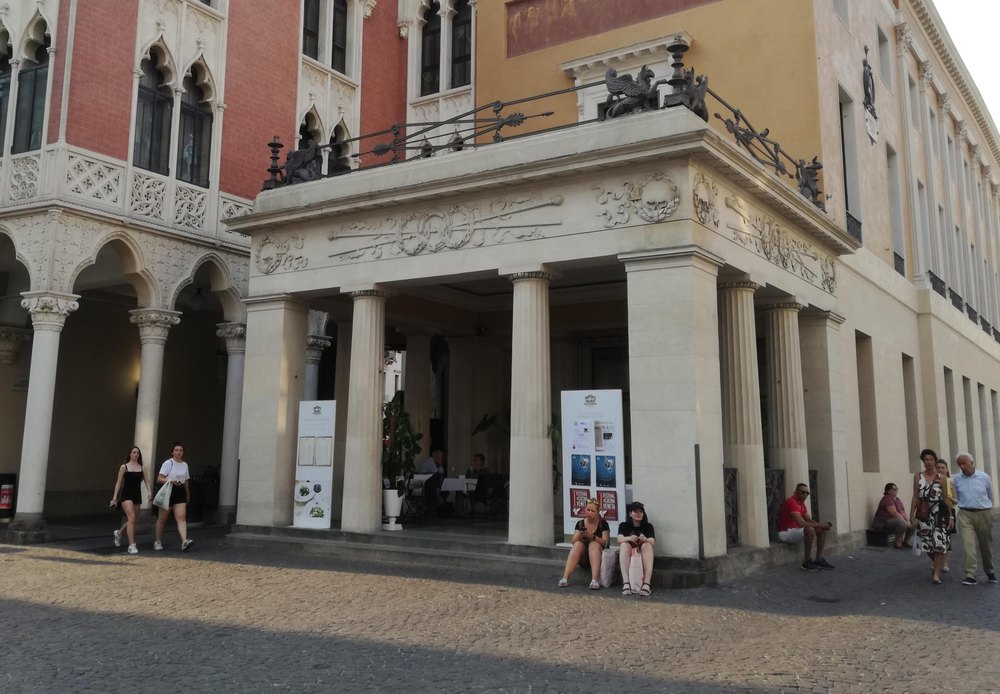 Neoklasyczny portyk z kolumnami Caffè Pedrocchi w Padwie, przed wejściem przechodnie i stoliki