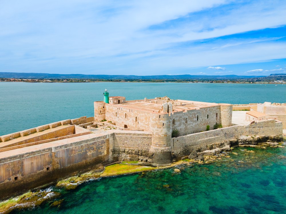 Kamienny fort Castello Maniace na południowym cyplu Ortigii nad turkusową wodą