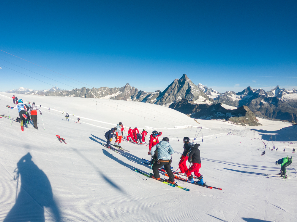 Letnie narty na lodowcu nad Cervinią, grupa narciarzy na trasie, w tle Matterhorn