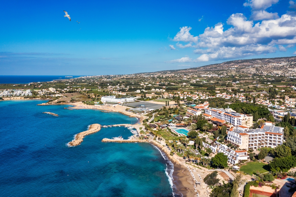 Coral Bay pod Pafos z lotu ptaka, plaża w zatoce, hotele na klifie i wzgórza Peyii