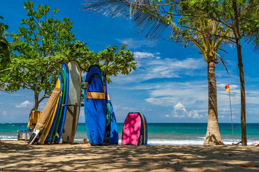 Deski surfingowe pod drzewami na plaży Kuta na Bali