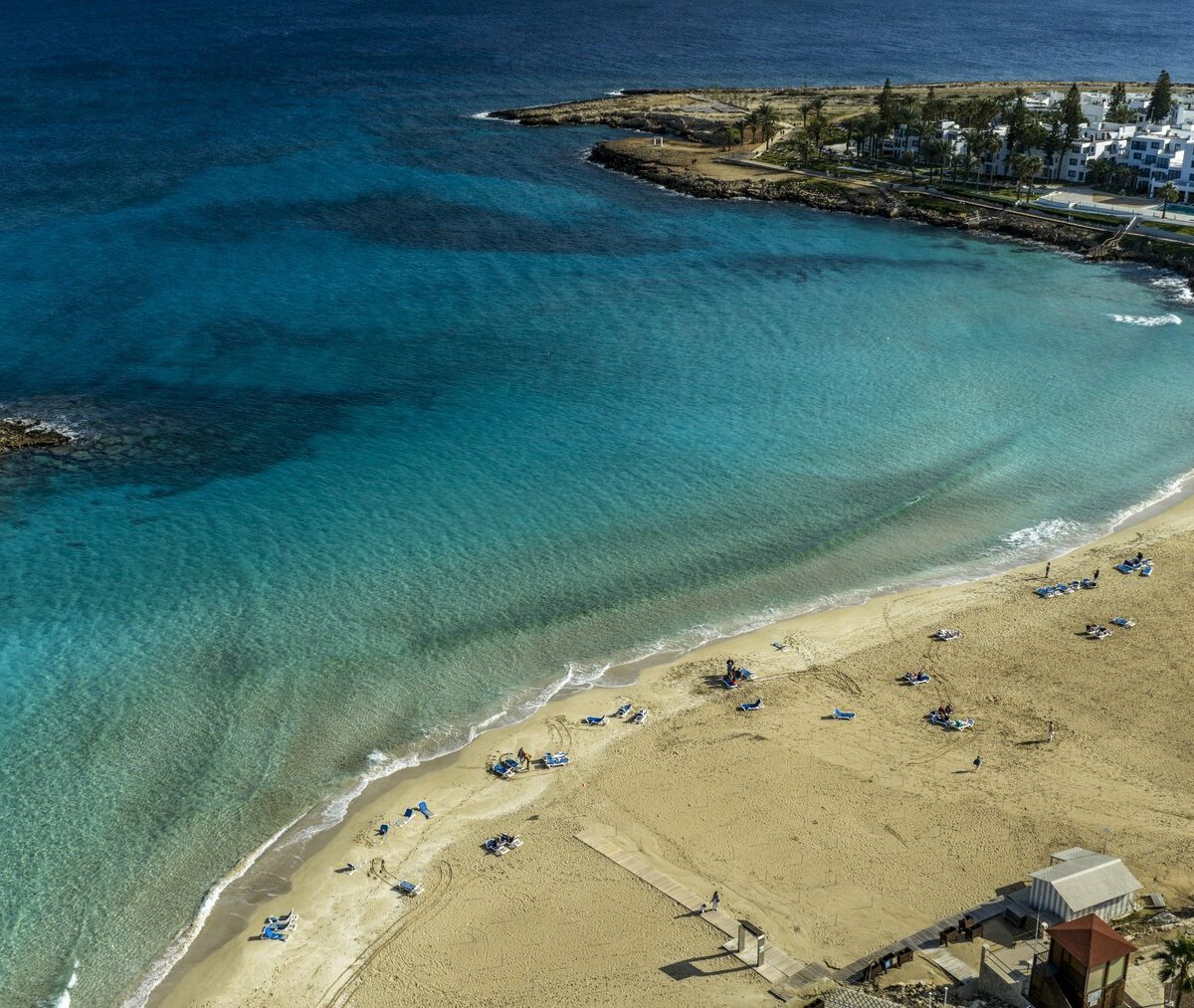 Fig Tree Bay w Protaras z drona, piaszczysta plaża, turkusowa woda i wysepka w zatoce