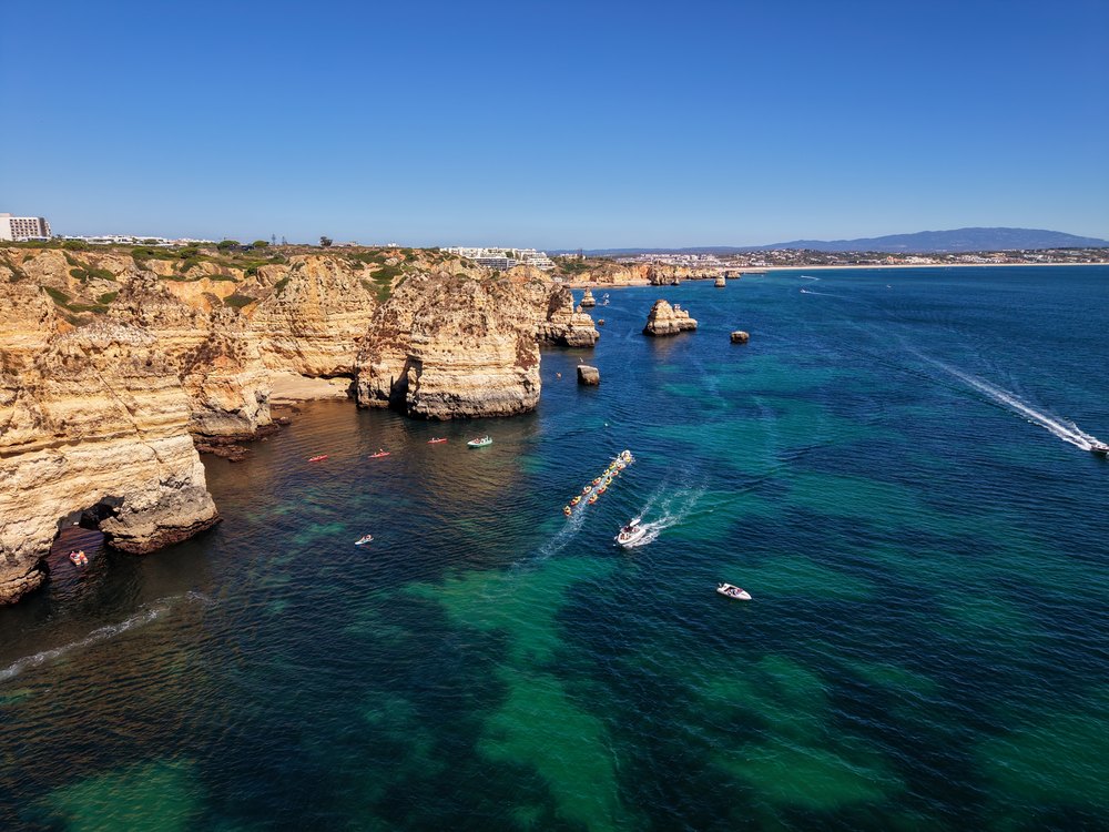 Łodzie pod klifami i grotami Ponta da Piedade, turkusowa woda przy brzegu pod Lagos