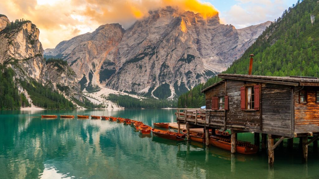 Drewniana przystań na palach nad Lago di Braies i szczyt Croda del Becco o wschodzie słońca