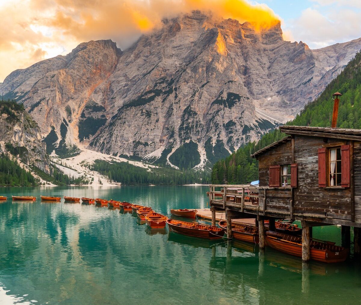 Drewniana przystań na palach nad Lago di Braies i szczyt Croda del Becco o wschodzie słońca