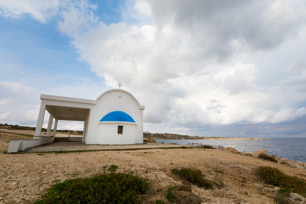 Biała kaplica Ayioi Anargyroi z niebieską kopułą na cyplu Cape Greco