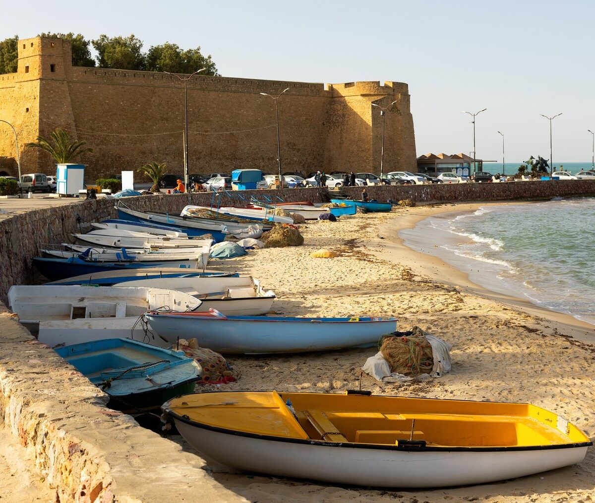 Mury kasby Hammametu nad zatoką, na plaży pod nabrzeżem kolorowe łodzie rybackie