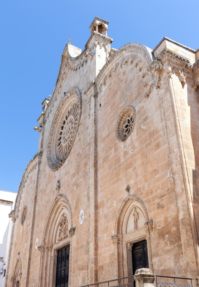 Fasada katedry Santa Maria Assunta w Ostuni z dużą rozetą i dwoma bocznymi portalami