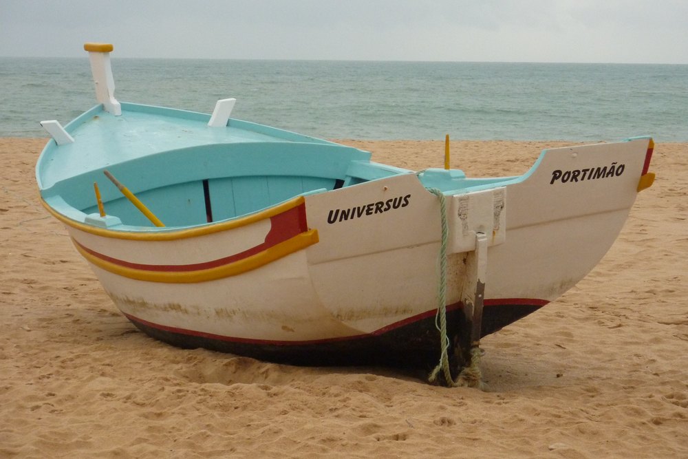 Kolorowa łódź rybacka wyciągnięta na piasek plaży w Armação de Pêra