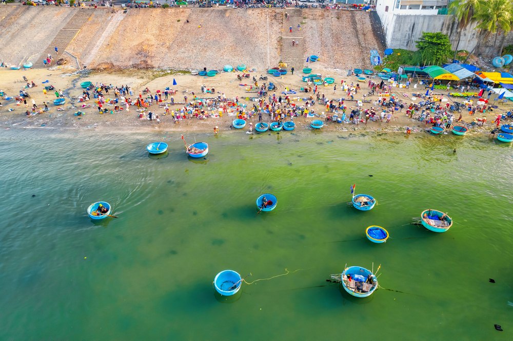 Okrągłe łodzie koszowe i targ rybny na plaży w Mui Ne z lotu ptaka