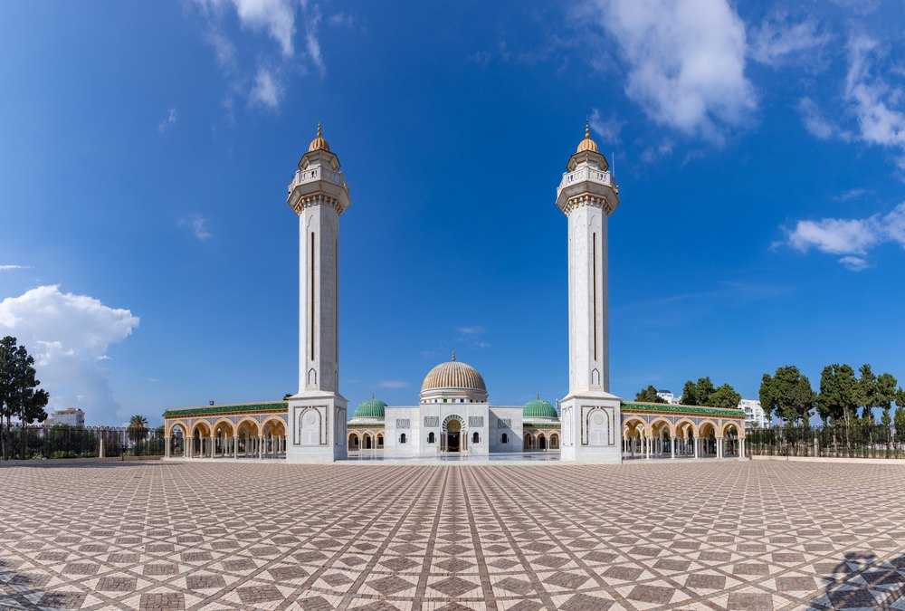 Mauzoleum Habiba Burgiby w Monastyrze: dwa smukłe minarety i złocona kopuła za placem z wzorzystą posadzką