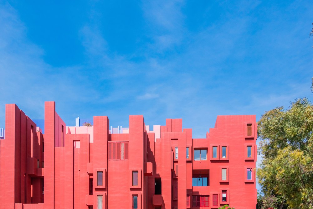 Czerwone ściany budynku Muralla Roja Ricarda Bofilla w Calpe pod błękitnym niebem