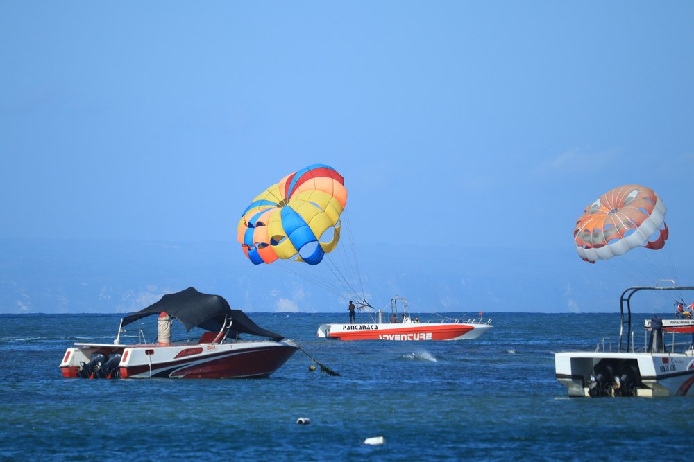 Parasailing i motorówki nad wodą przy plaży Tanjung Benoa