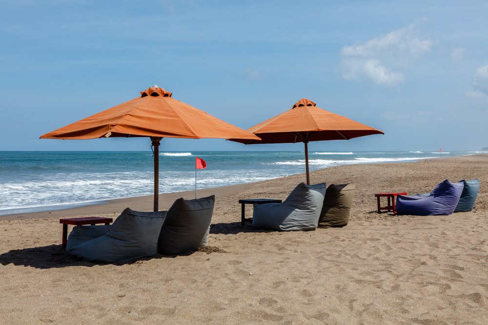 Parasole i pufy na szerokiej plaży Berawa w Canggu