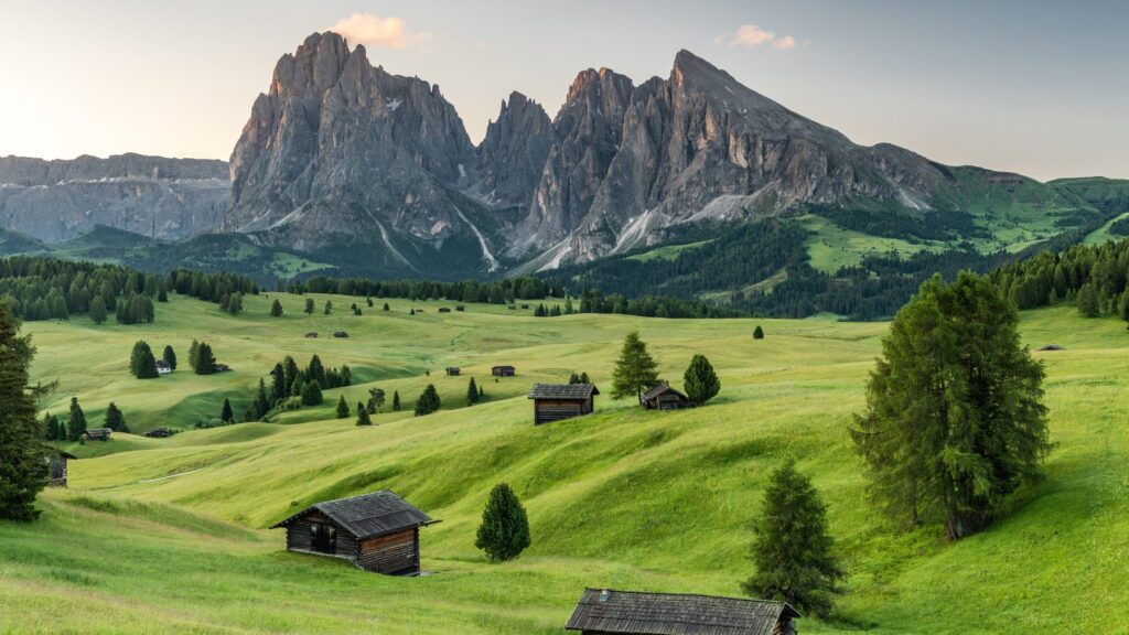 Pastwiska Alpe di Siusi z drewnianymi szałasami, w tle masyw Sassolungo