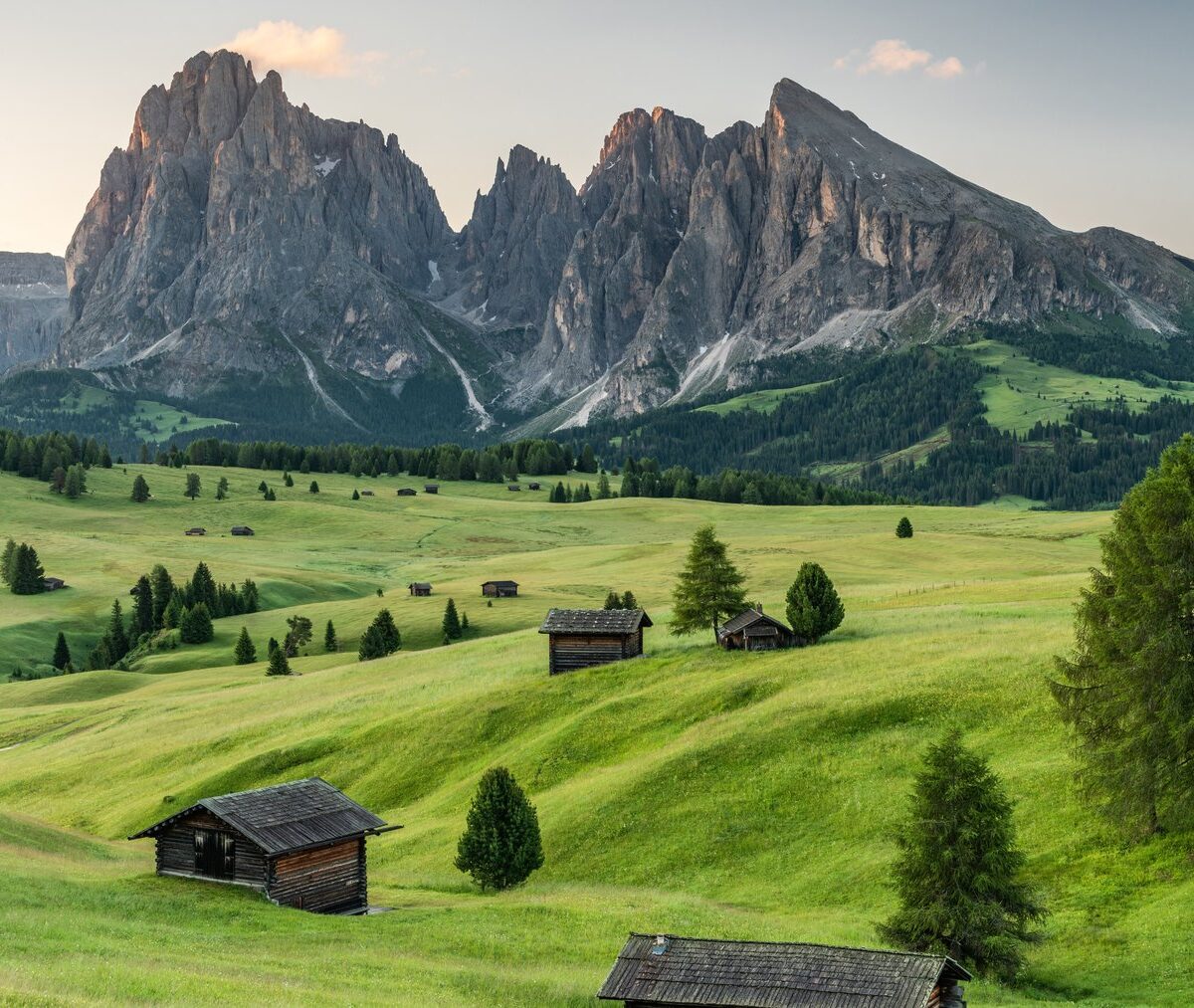 Pastwiska Alpe di Siusi z drewnianymi szałasami, w tle masyw Sassolungo
