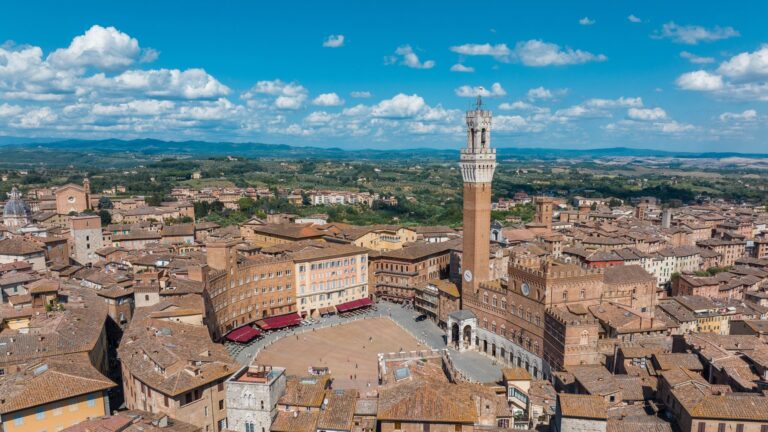 Piazza del Campo w kształcie muszli i Torre del Mangia nad Palazzo Pubblico, wokół ceglane dachy Sieny