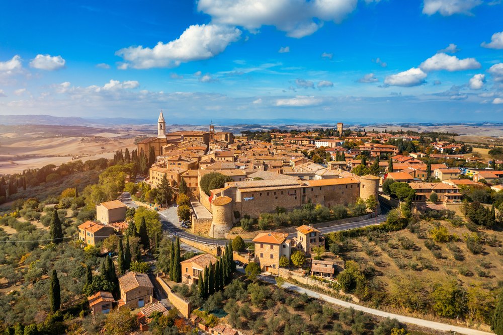 Pienza na wzgórzu nad doliną Val d'Orcia, ceglane domy i dzwonnica katedry wśród cyprysów
