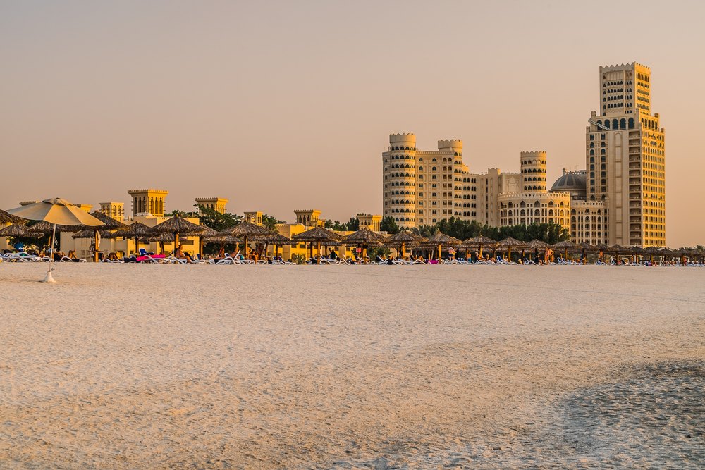 Plaża w Al Hamra o zachodzie słońca, z parasolami i hotelem w tle