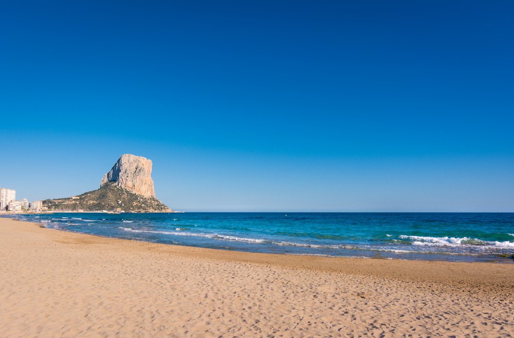 Piaszczysta plaża Arenal Bol w Calpe, w głębi skała Peñón de Ifach nad morzem